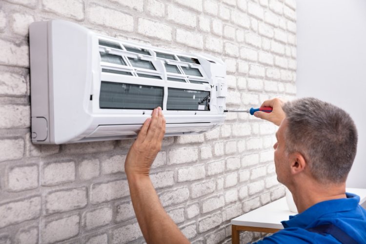 Pracownik montuje klimatyzator na ścianie